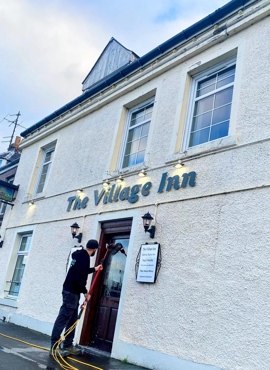 Craig cleaning the windows above the door of The Village Inn in Bridge of Earn