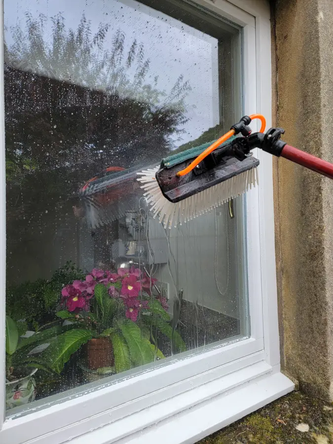Pure water brush on a window with flowers on the sill inside