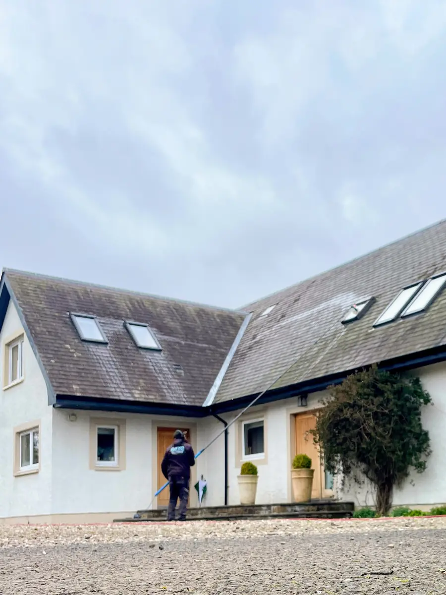 Craig cleaning the windows of a large white country house with a water-fed pole