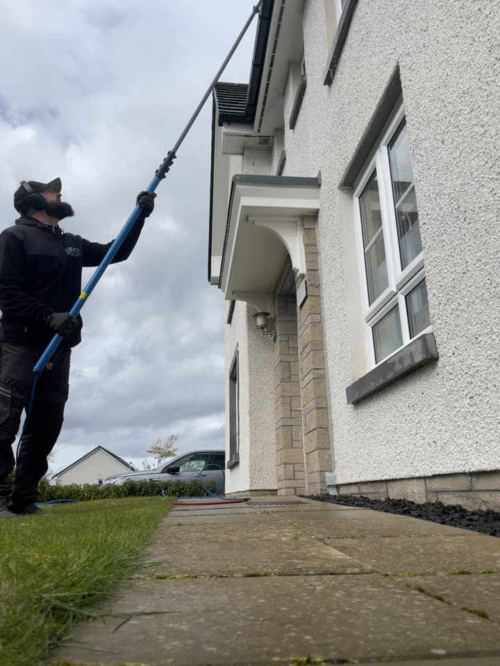 Craig cleaning the upstairs windows of a new-build home with a water-fed pole