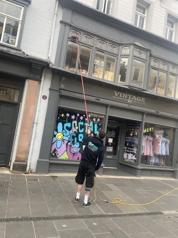 Cleaning a shopfront window with a water-fed pole