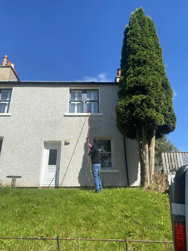 Cleaning windows on a white rendered house